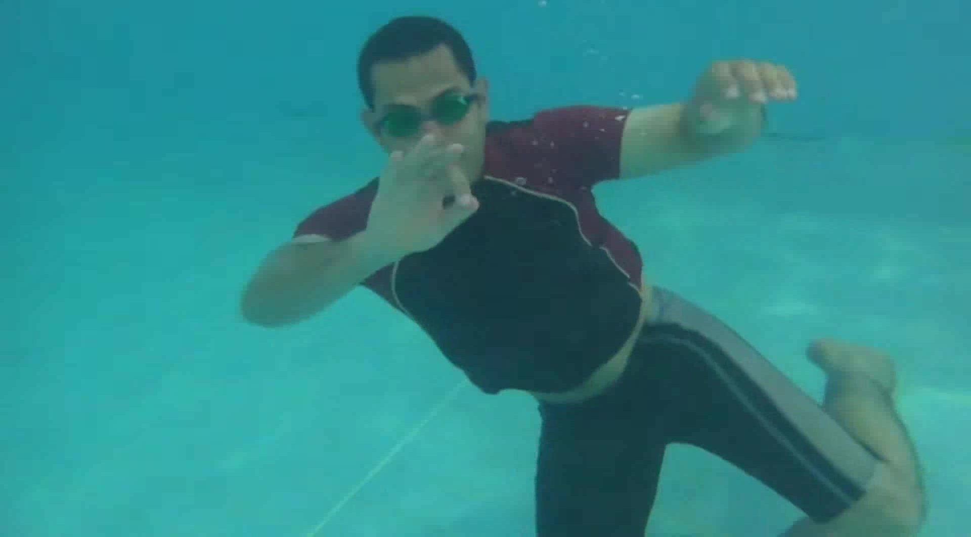 Clothed arab swimming underwater