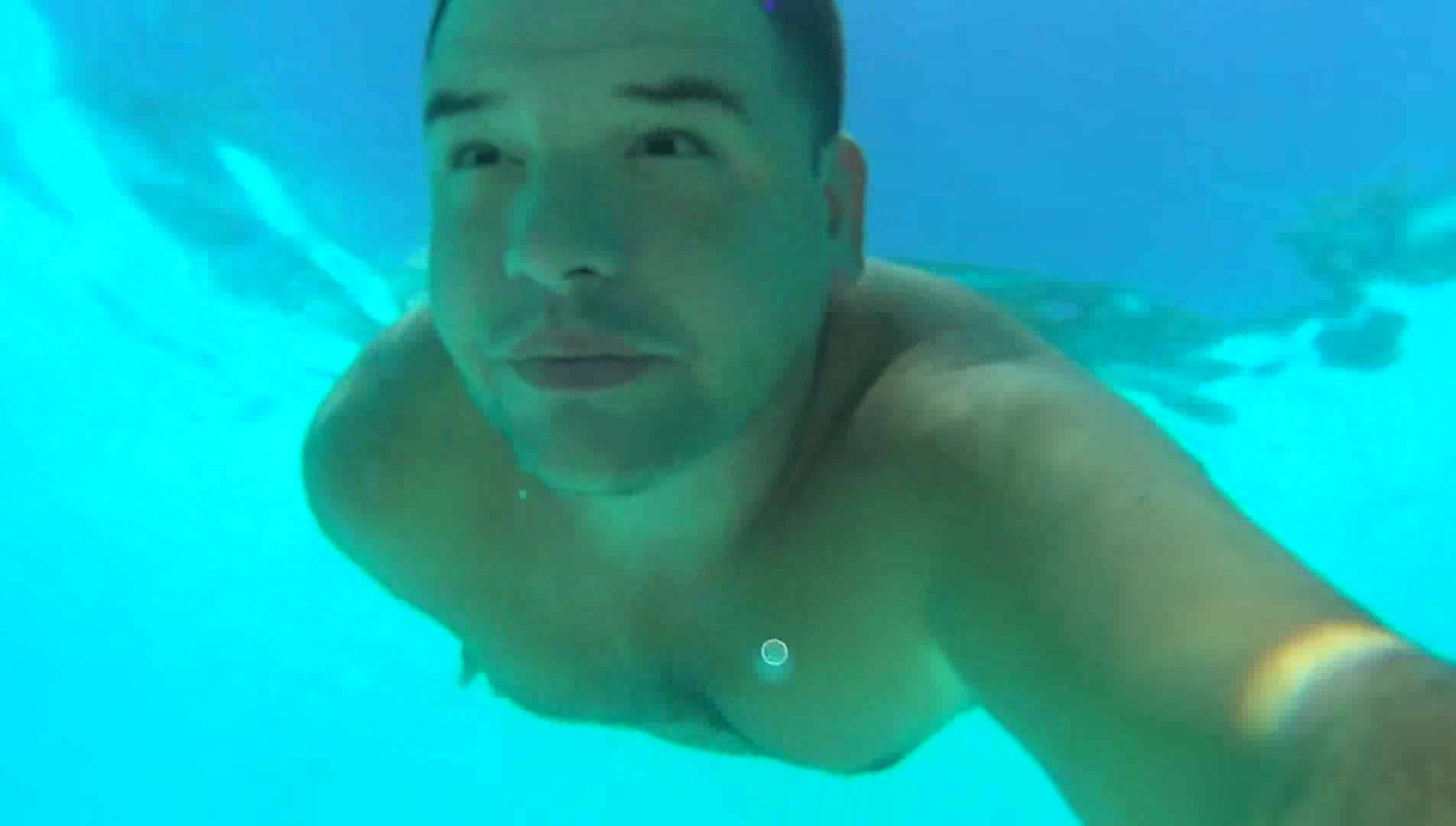 Beefy guy swims barefaced underwater