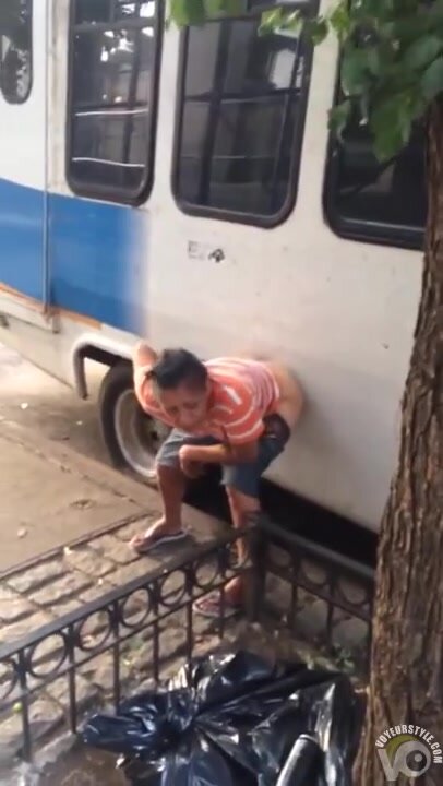 peeing up against a bus