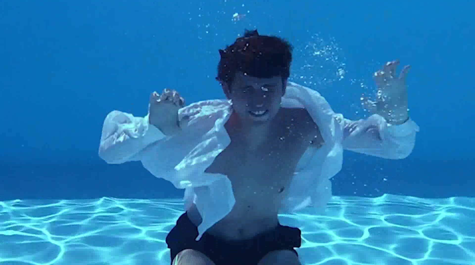 Barefaced clothed guy posing underwater