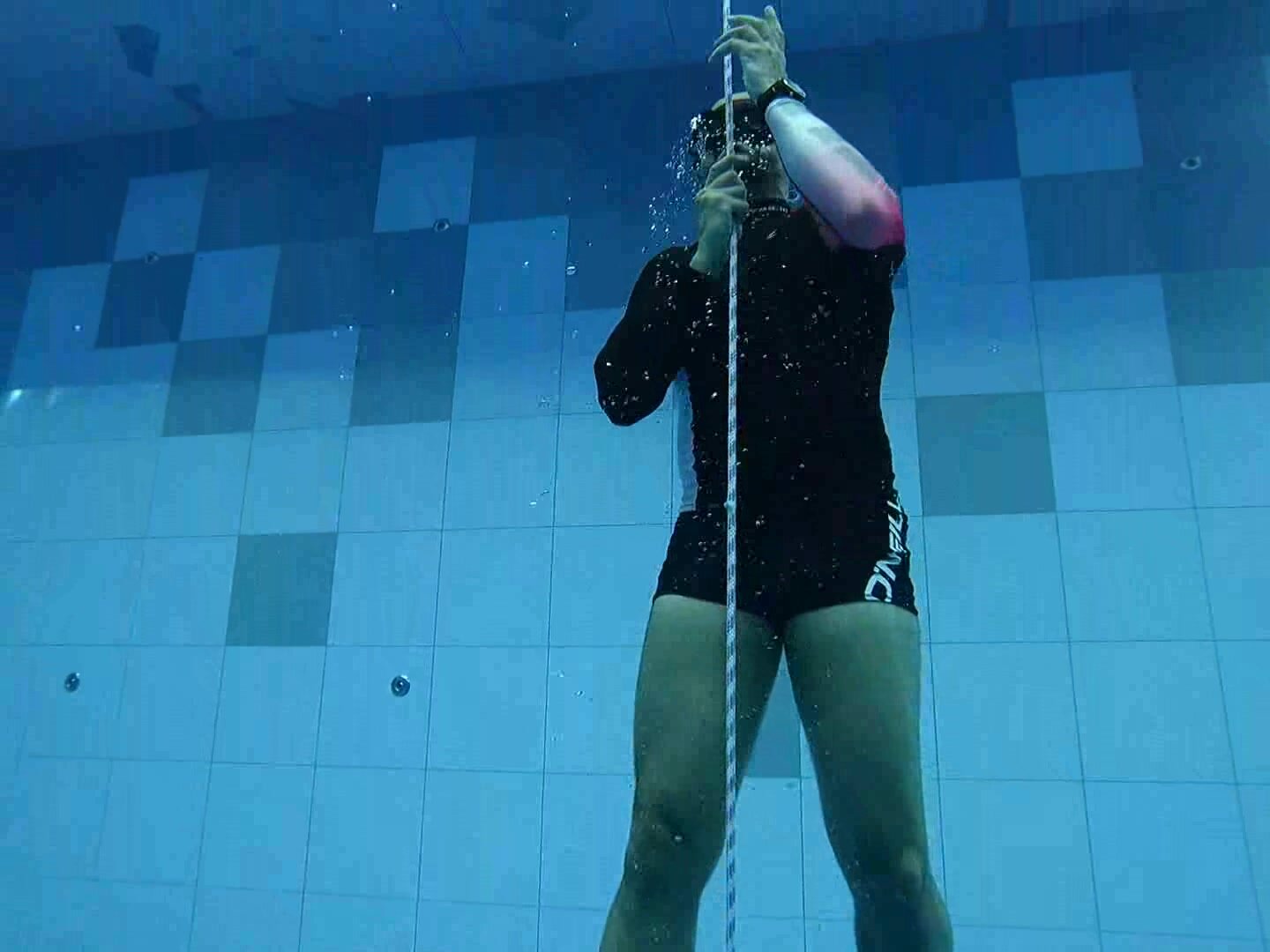 Bald freediver breatholding deep underwater