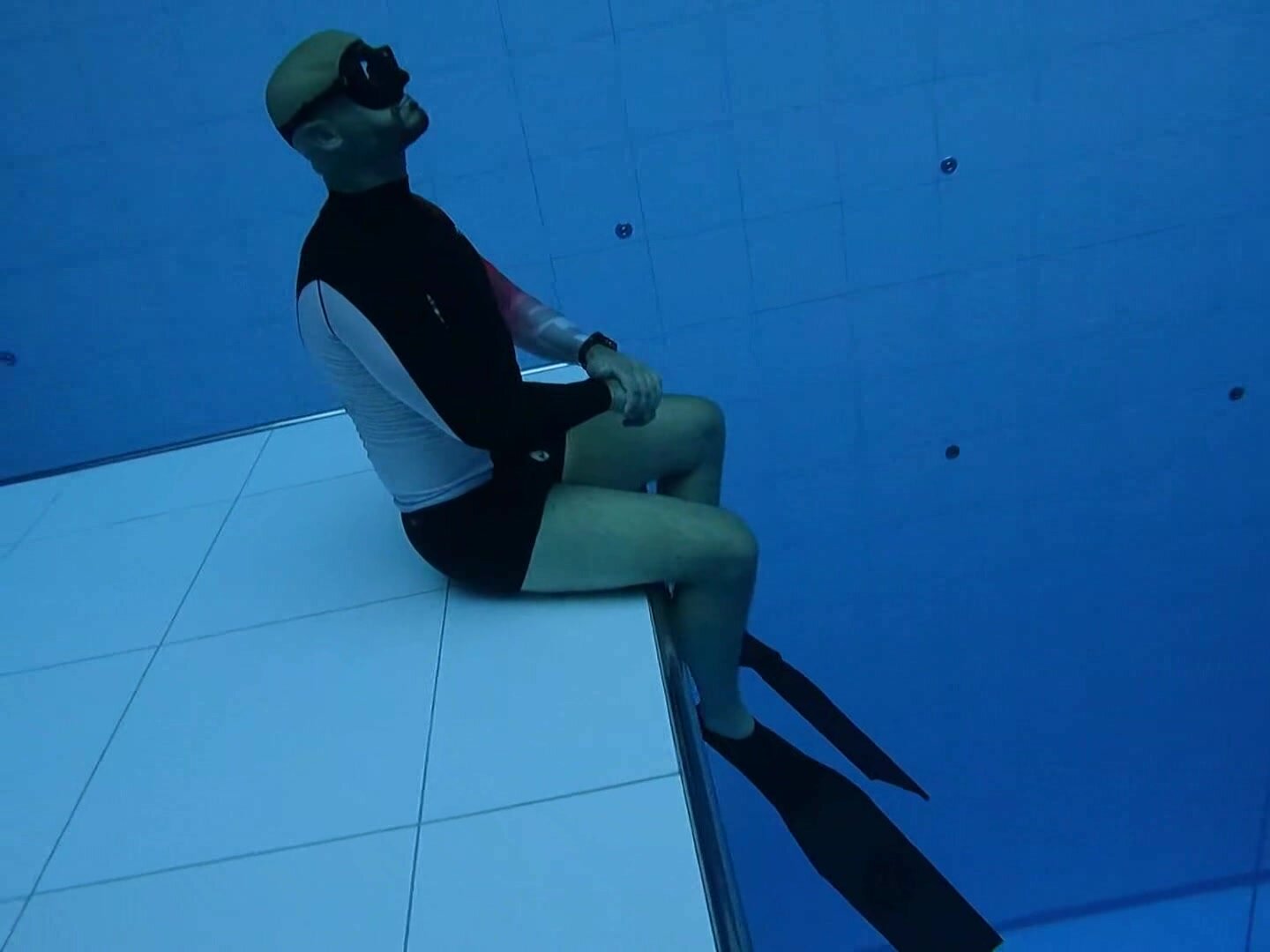 Underwater bald freediver relax at the bottom