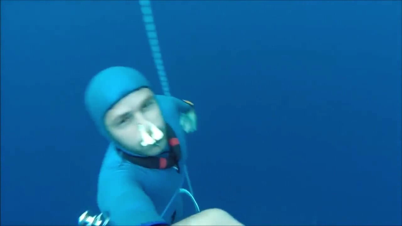 Barefaced freediver diving very deep underwater