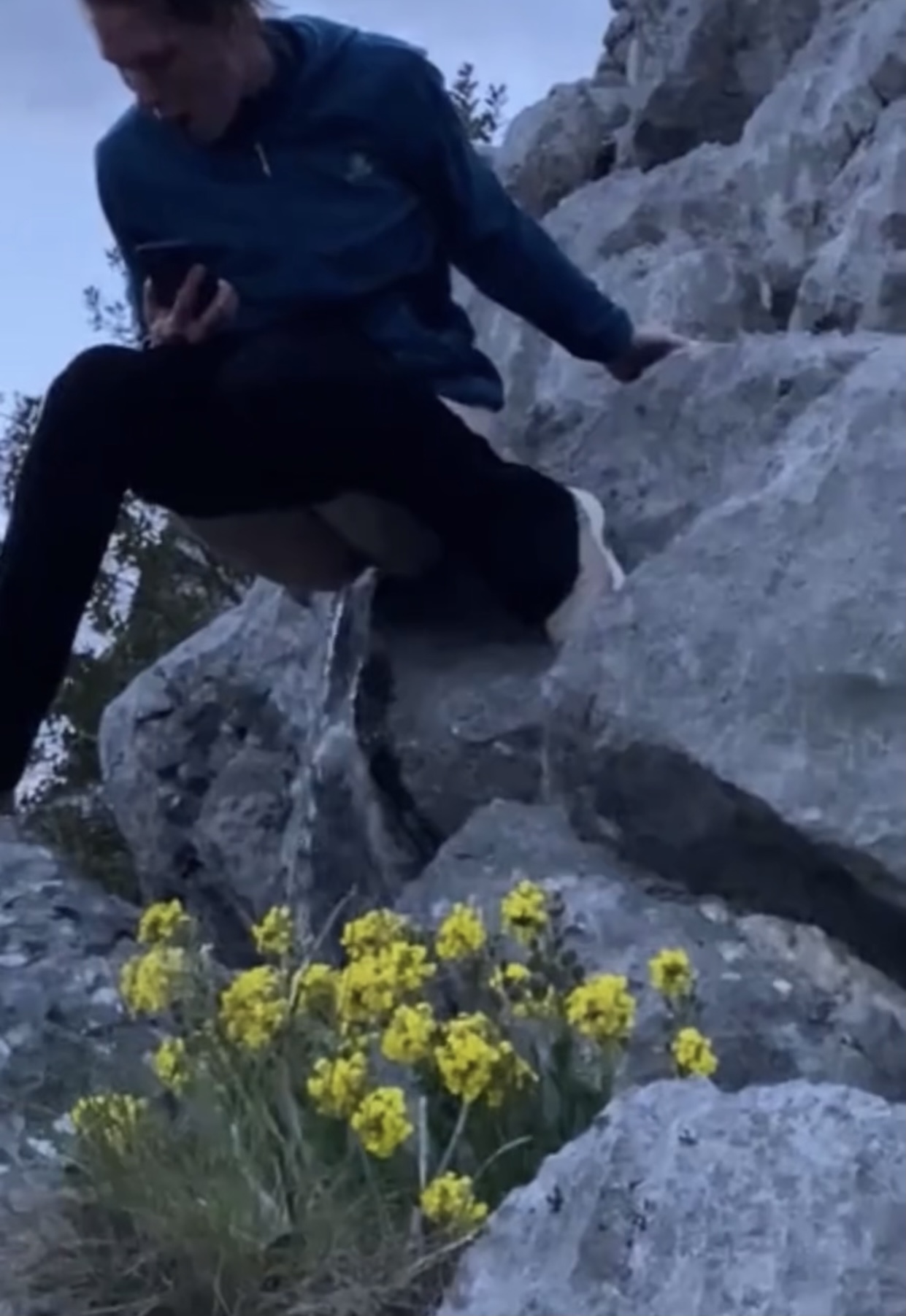 Woman pees suspended between rocks