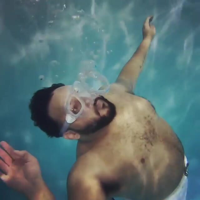 Beefy hairy guy blowing bubbles underwater