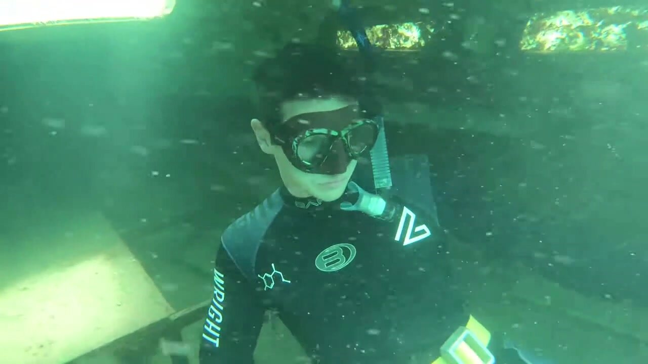 Fit buddies freediving underwater in wetsuits