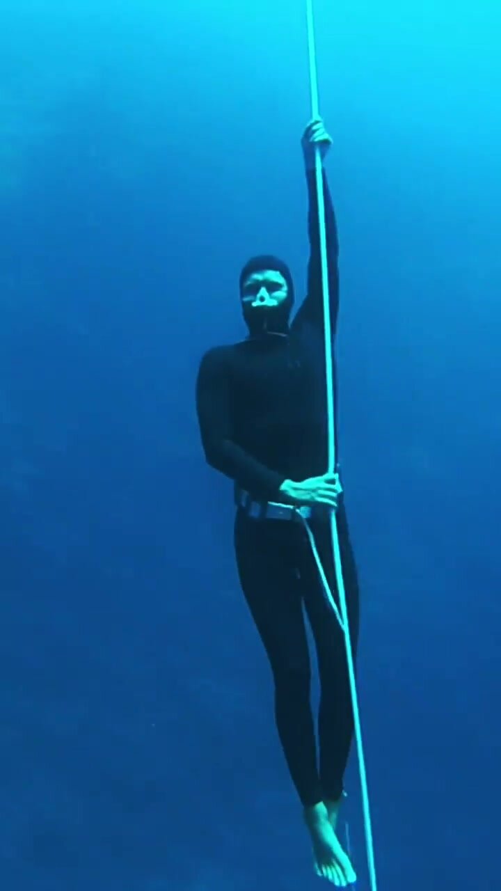 Barefaced freediver underwater in wetsuit