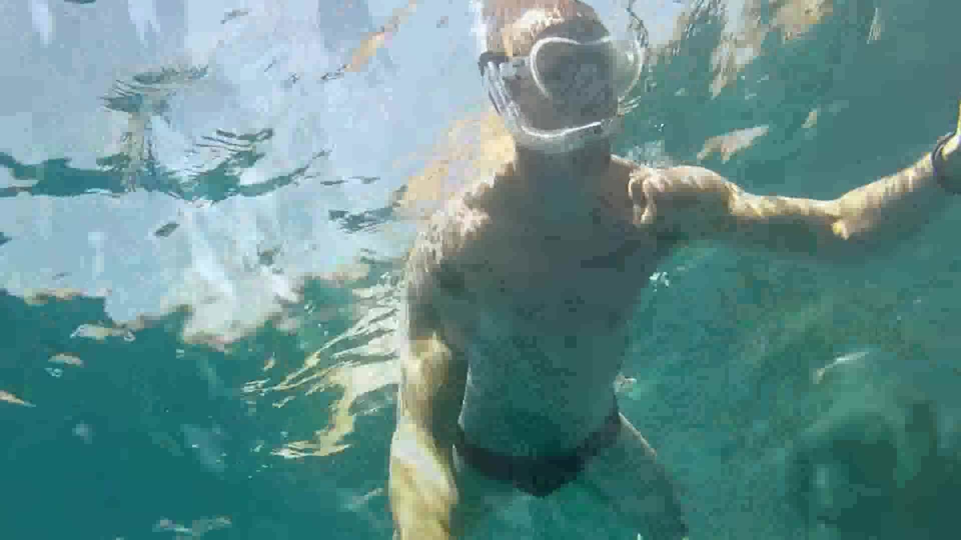 Cute guy freediving underwater in black speedo
