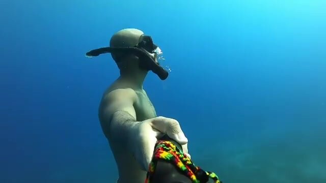 Bald freediver underwater in shorts