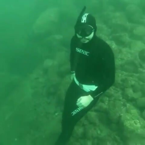 Beefy freediver underwater in tight wetsuit