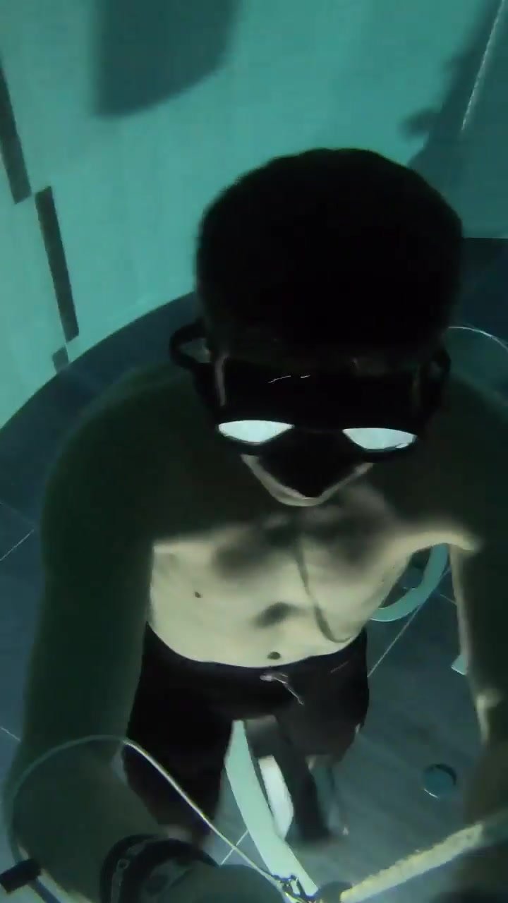 French apneist deep underwater in bulging wetsuit