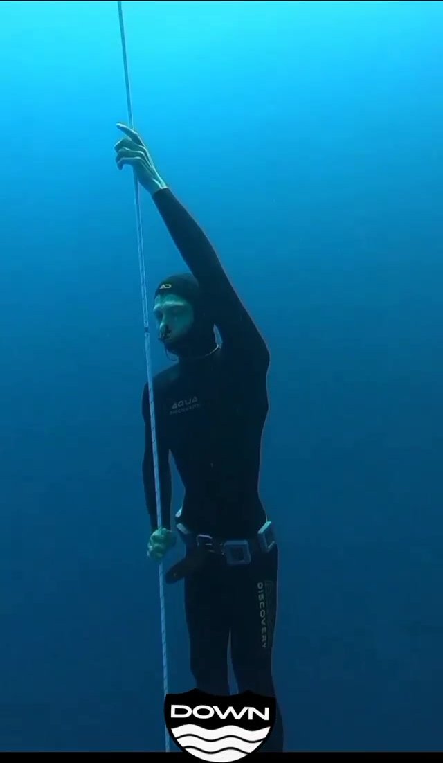 Barefaced underwater in black wetsuit