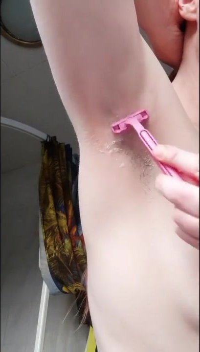 Beautiful girl shaving her hairy armpit