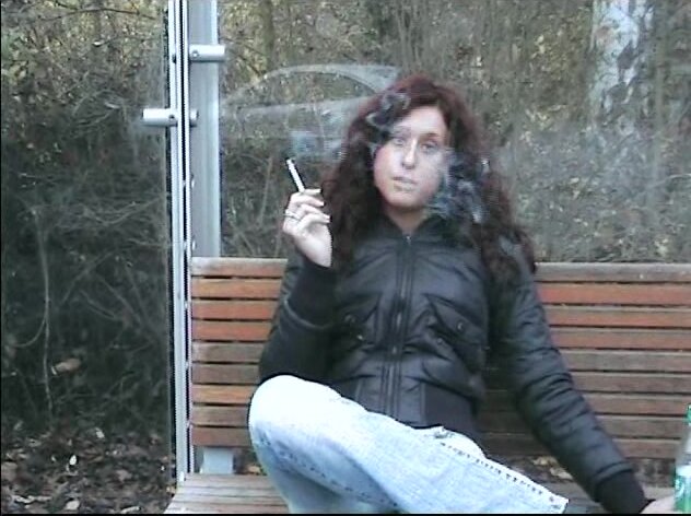 Waiting a bus, a girl smokes and spits