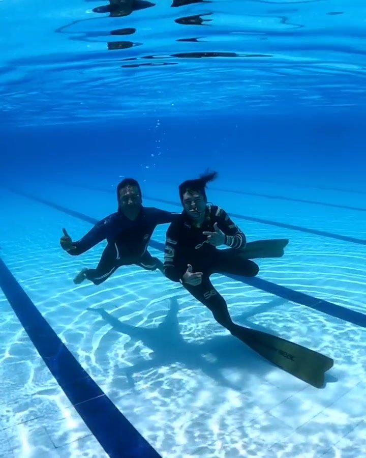 Barefaced buddies underwater in wetsuits
