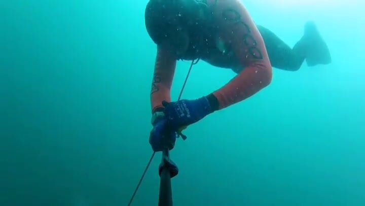 Barefaced deep underwater in wetsuit