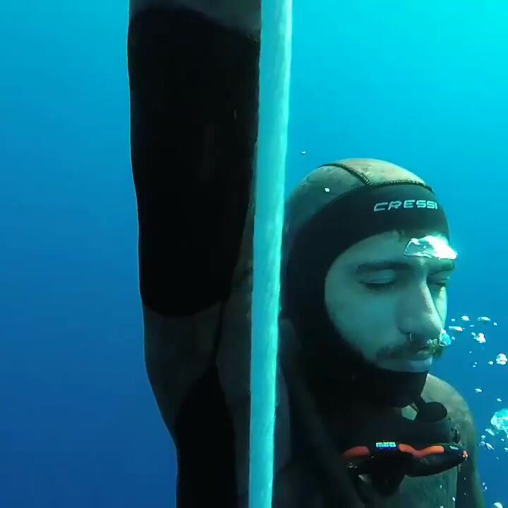 Underwater barefaced arab freediver in wetsuit