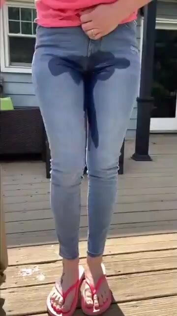 Girl wetting her jeans in the backyard