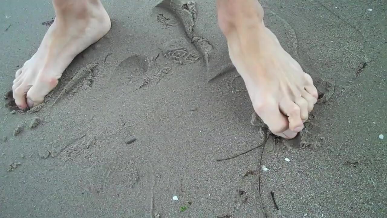 hot guy walks on beach barefoot
