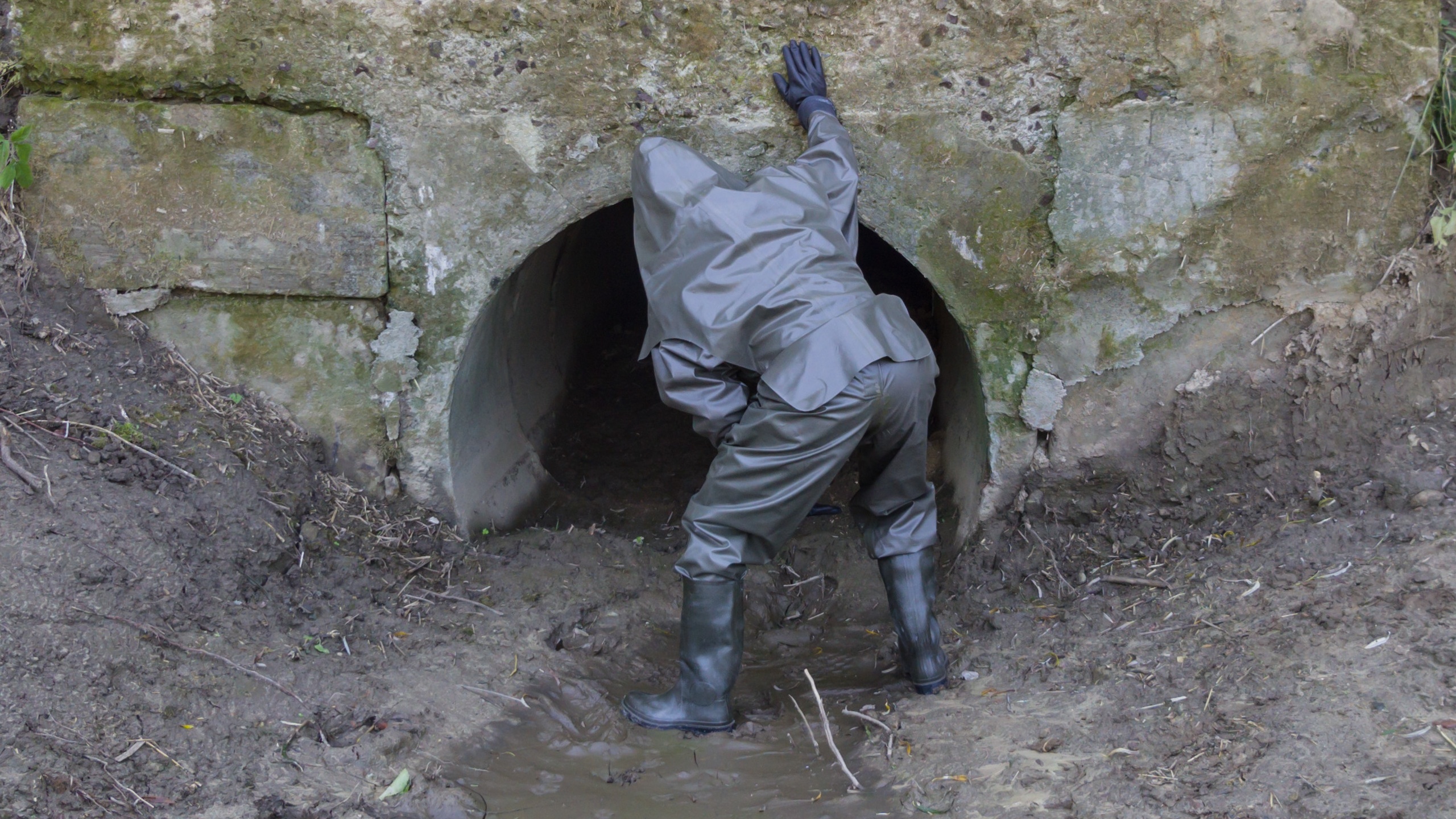 Crossing muddy tunnel in rubber suit