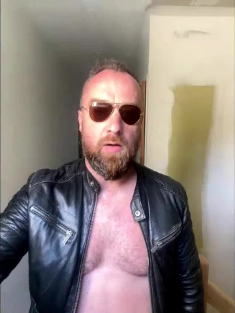 A bearded guy dressed in leather smokes