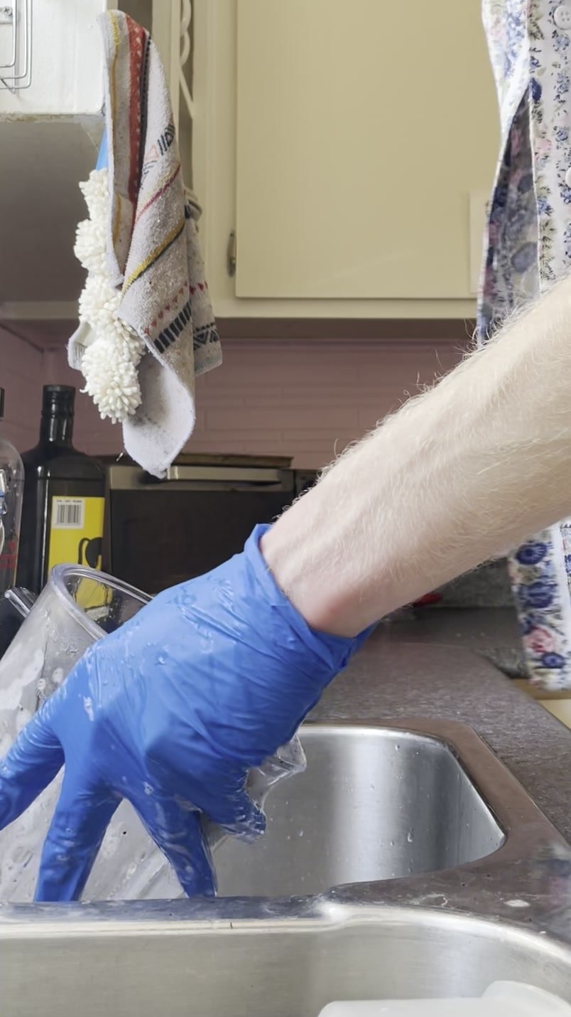 Washing dishes wearing blue nitrile gloves