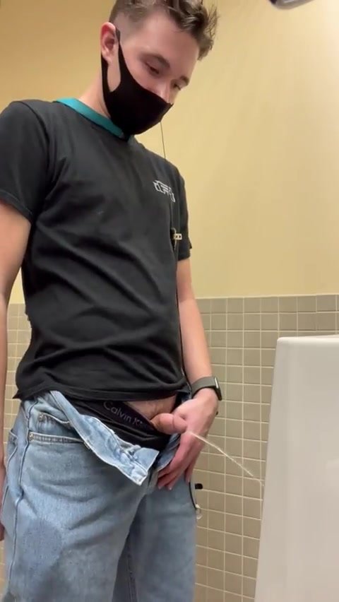 young guy showing off his softie at urinal