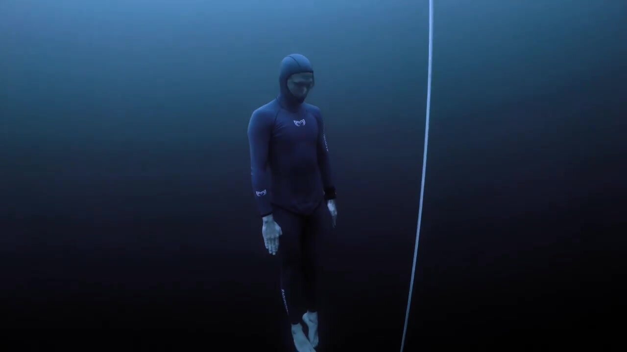Underwater barefaced freedivers in tight wetsuit