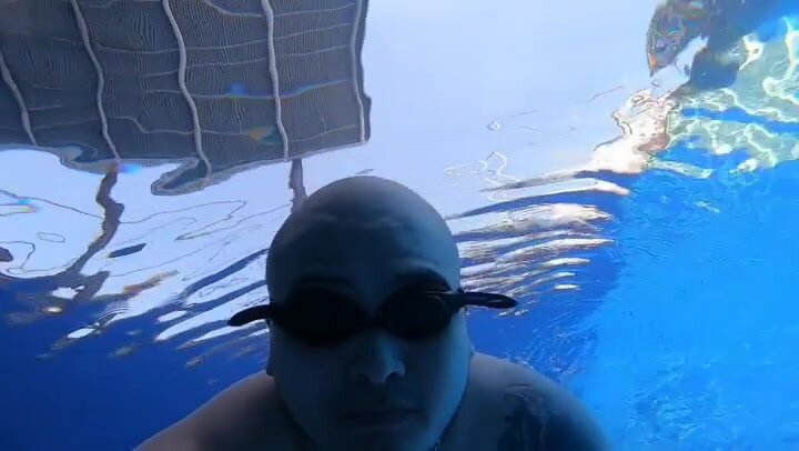 Bald beefy guy breatholding underwater with goggles
