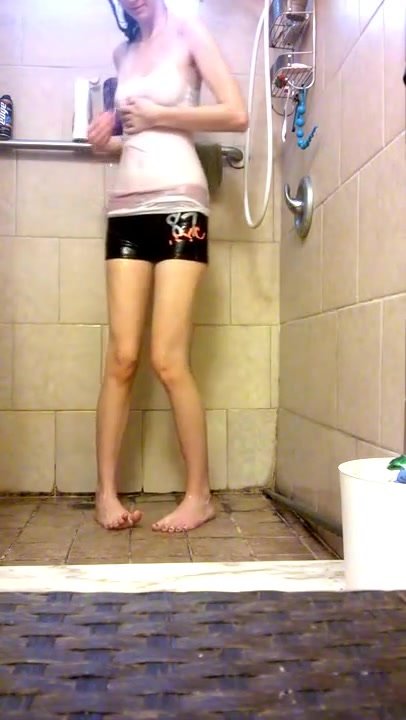 Girl takes a clothed shower and pees
