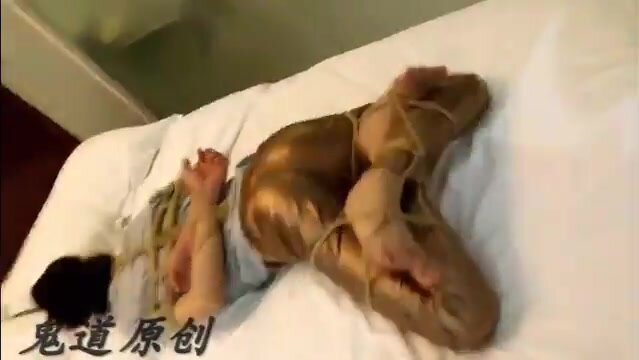 guy in shiny pants hogtied on bed