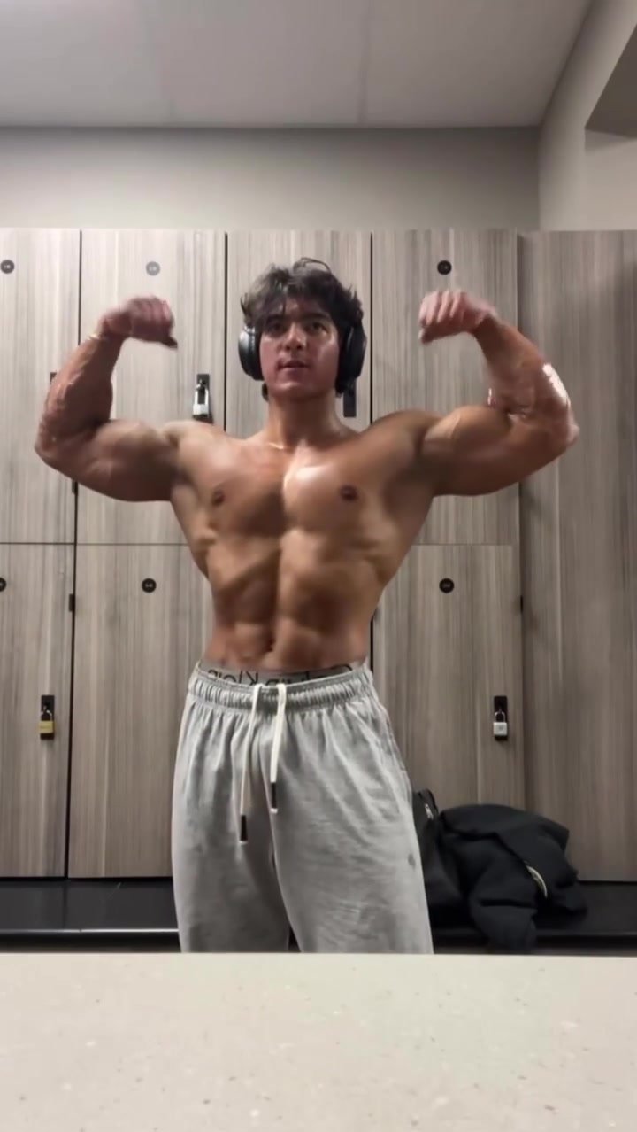giant bodybuilder jock flexing in locker room