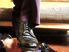 Black wingtip dress shoes steps on head and cock