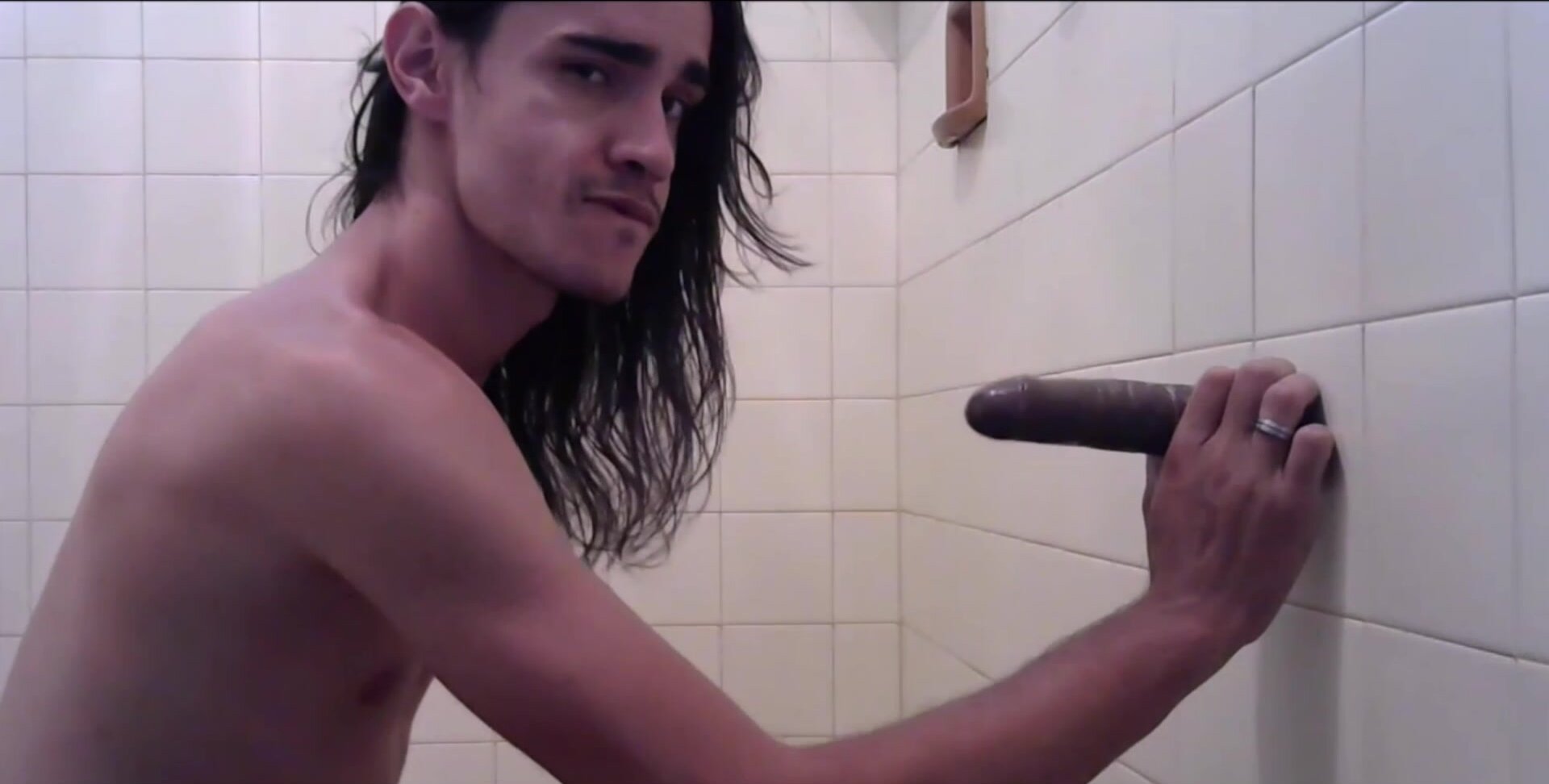 Long haired man sucking a dildo
