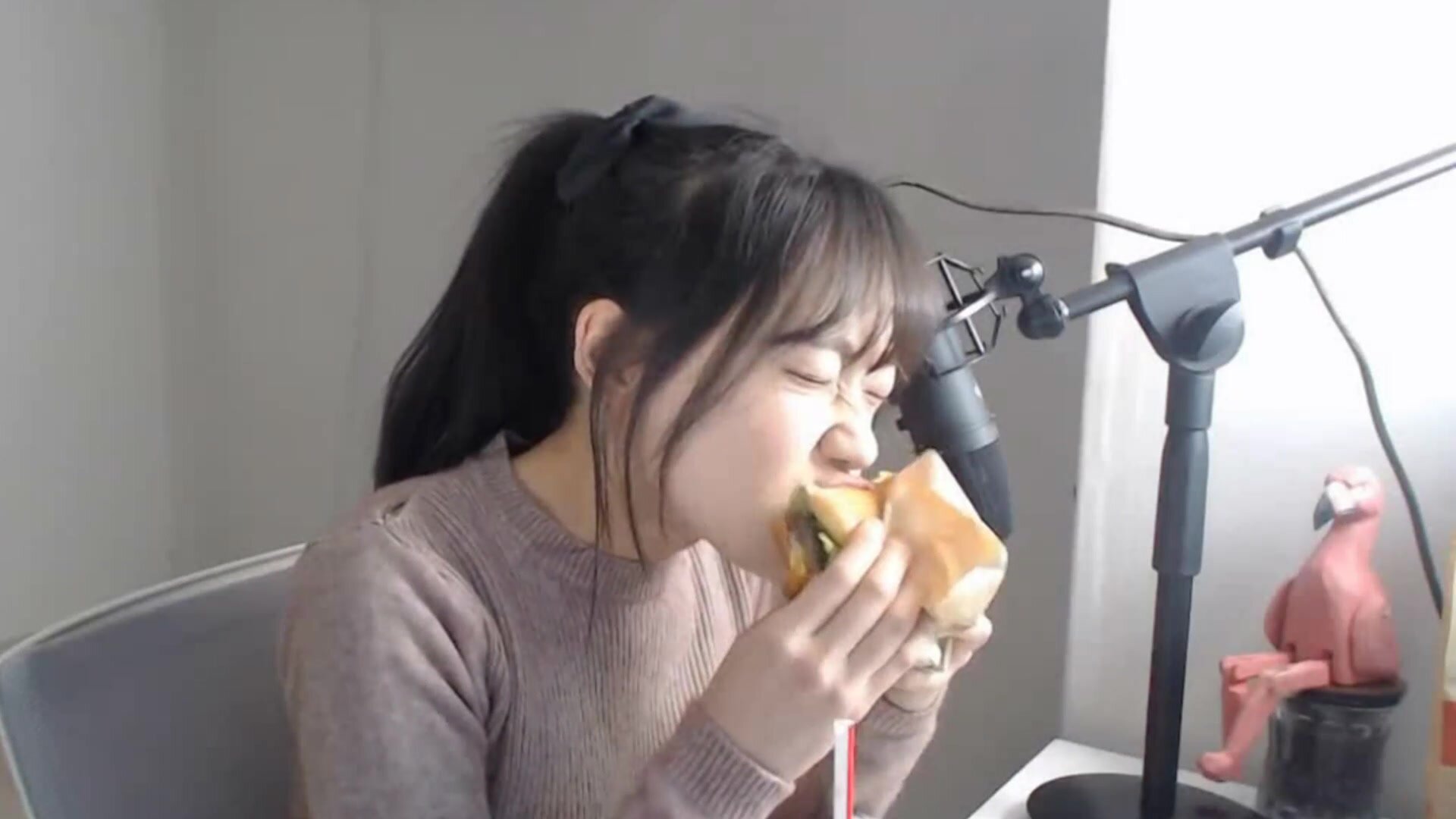 Young Korean streamer taking big bites of a burger