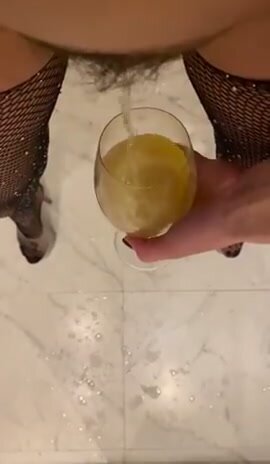 Sexy babe fills wine glass, tinkles the rest on floor