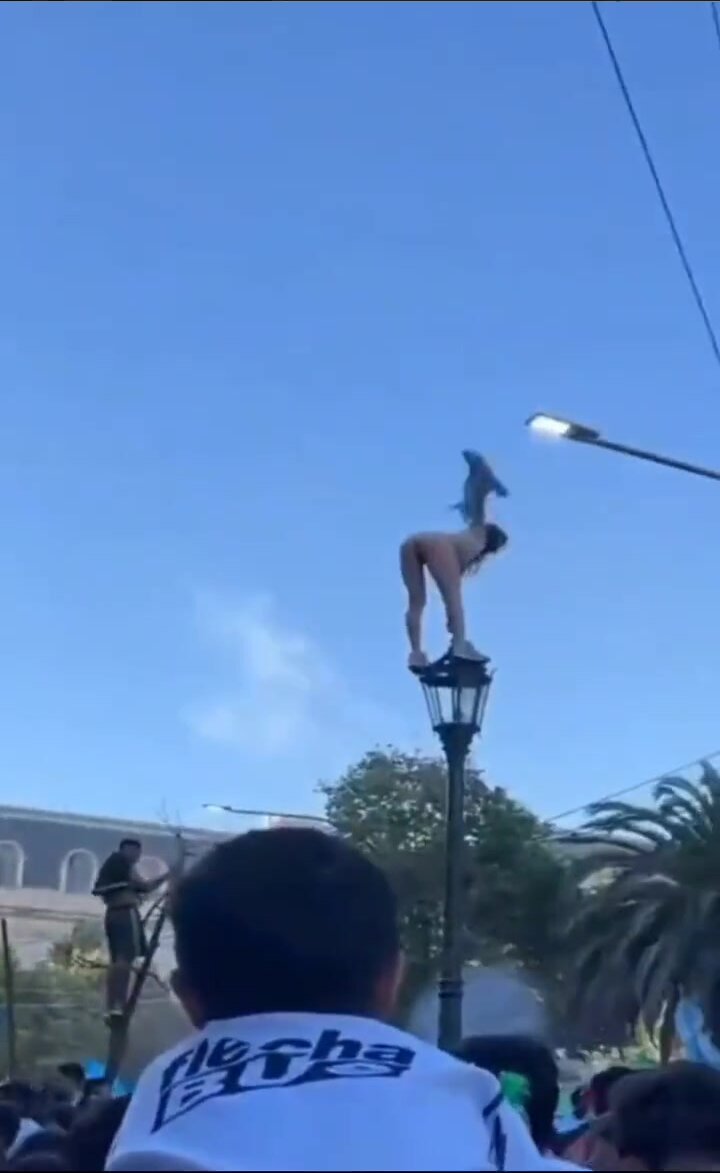 Argentinean girl climbs up a light pole naked