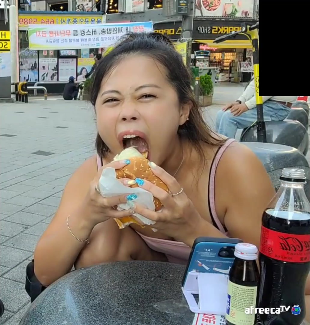 Athletic Korean girl chomps a McD's burger in public