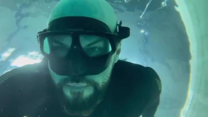 Bald bearded freediver underwater in wetsuit
