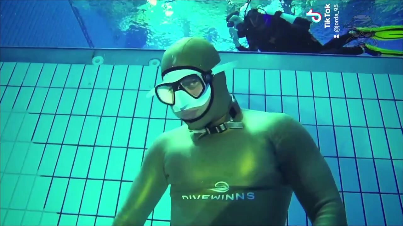 Breatholding underwater in tight golden wetsuit