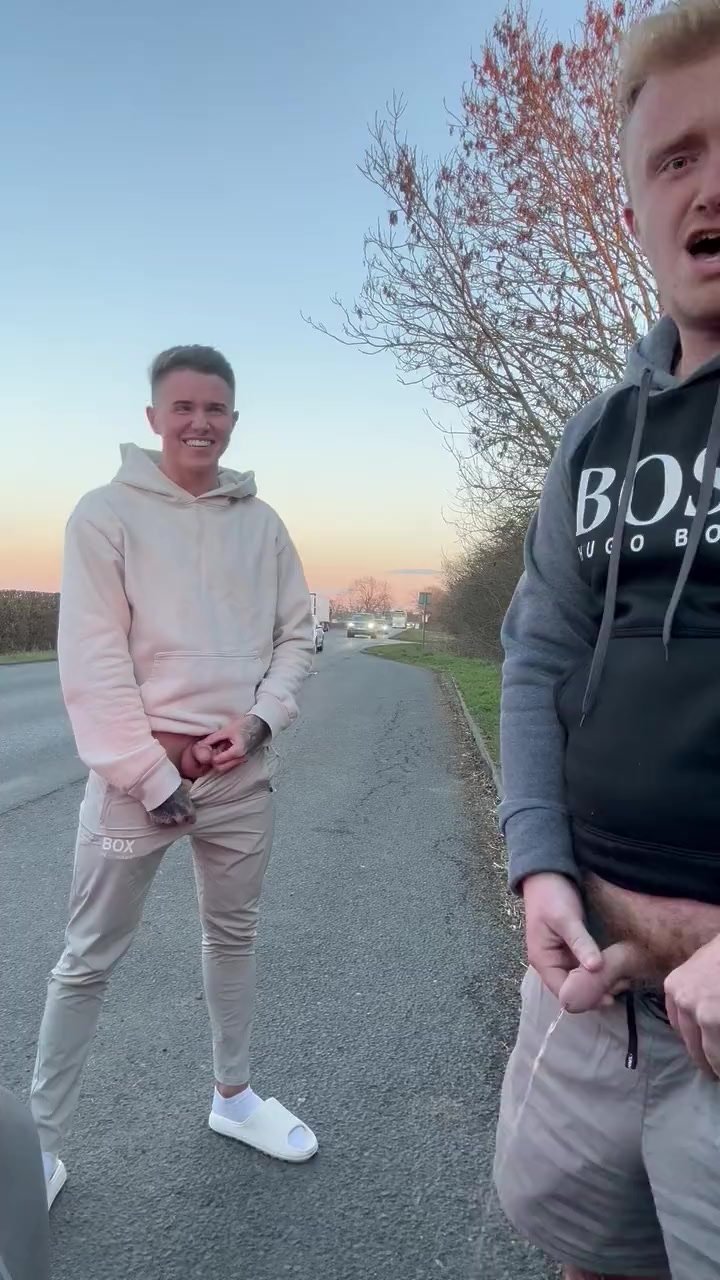 two guys pissing next to busy road