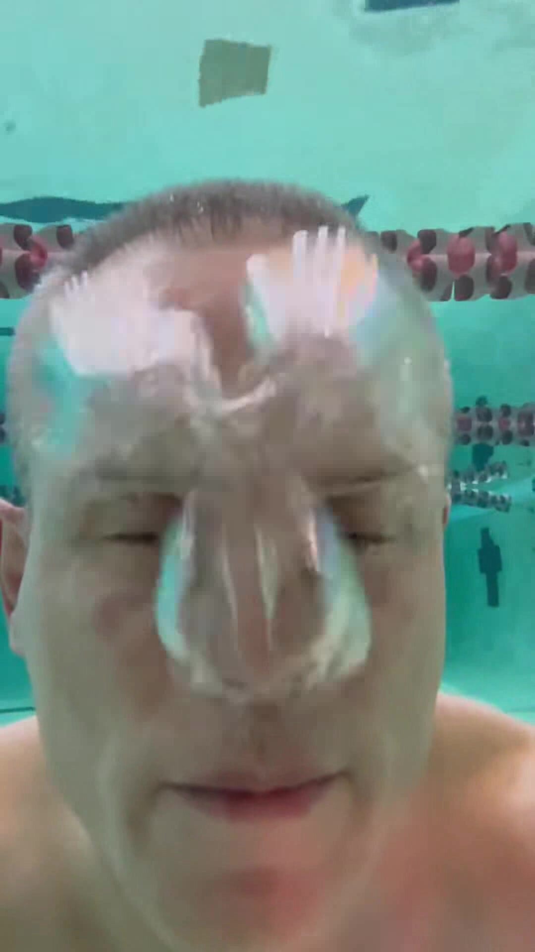 Barefaced guy blowing out air underwater