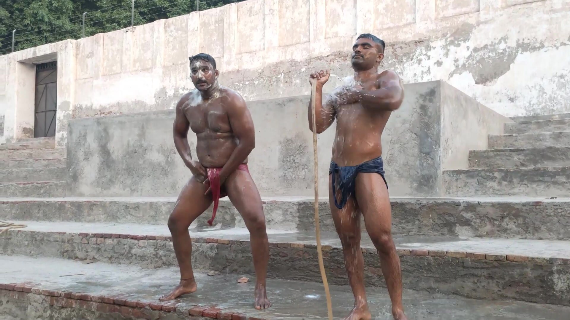 2 indian wrestlers showering outdoor