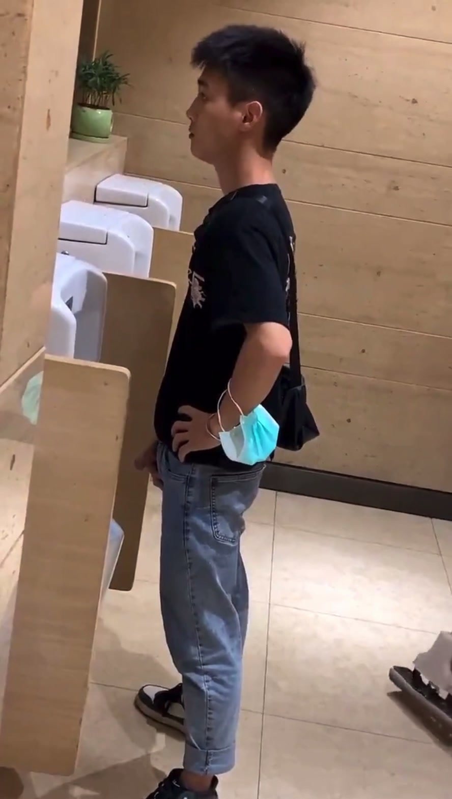 Young man pissing in urinal