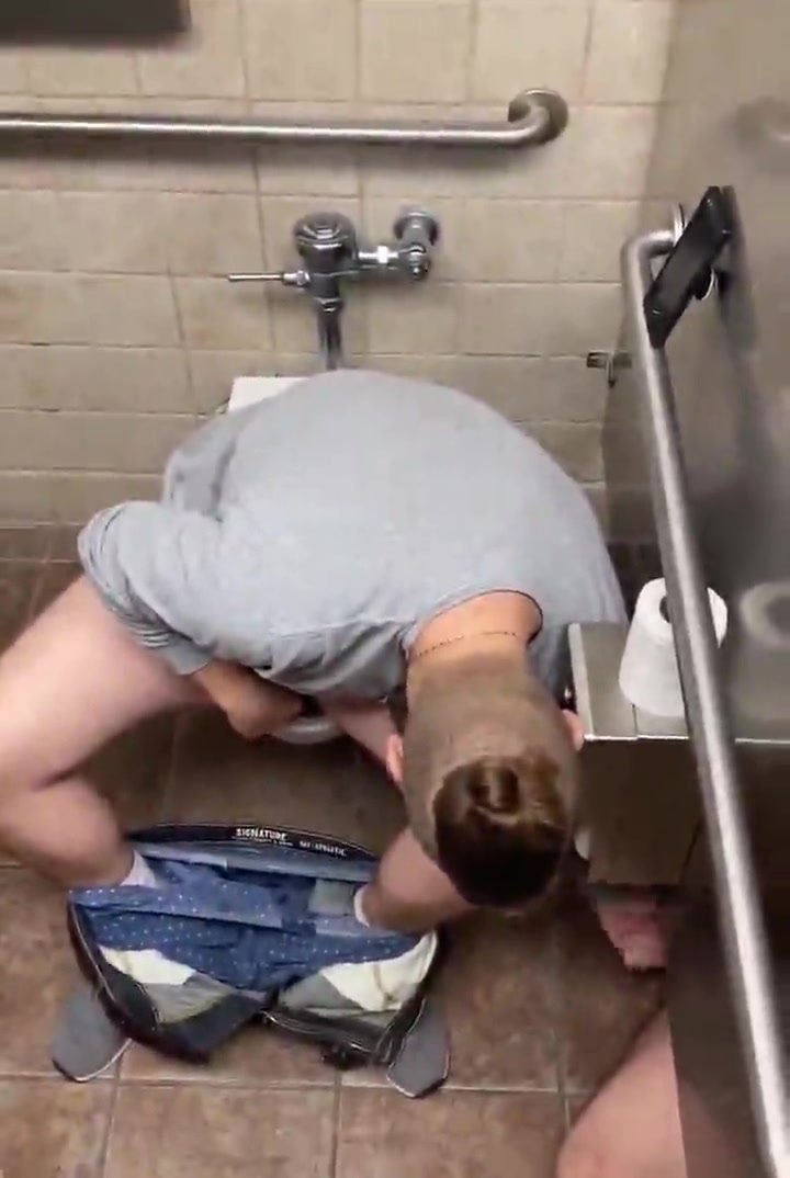Guy playing with cock of the dude of his next stall