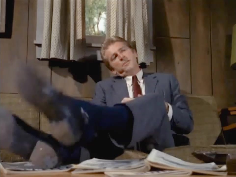 Actor in suit kicks off shoes