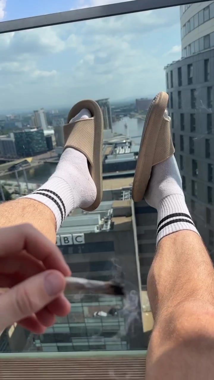 Hot Alpha Gods socked feet in slides, smoking a joint