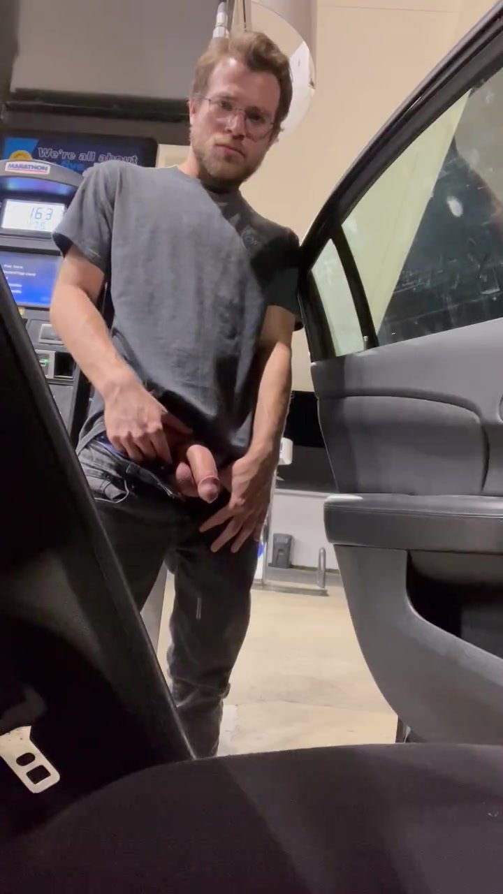 pissing next to his car at a petrol station