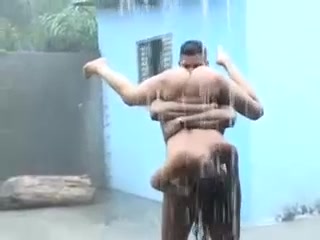 Naked man lifts his girlfriend in the air in a downpour