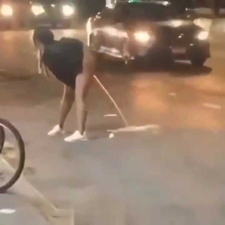 Girl on the street tries to hose down traffic with piss